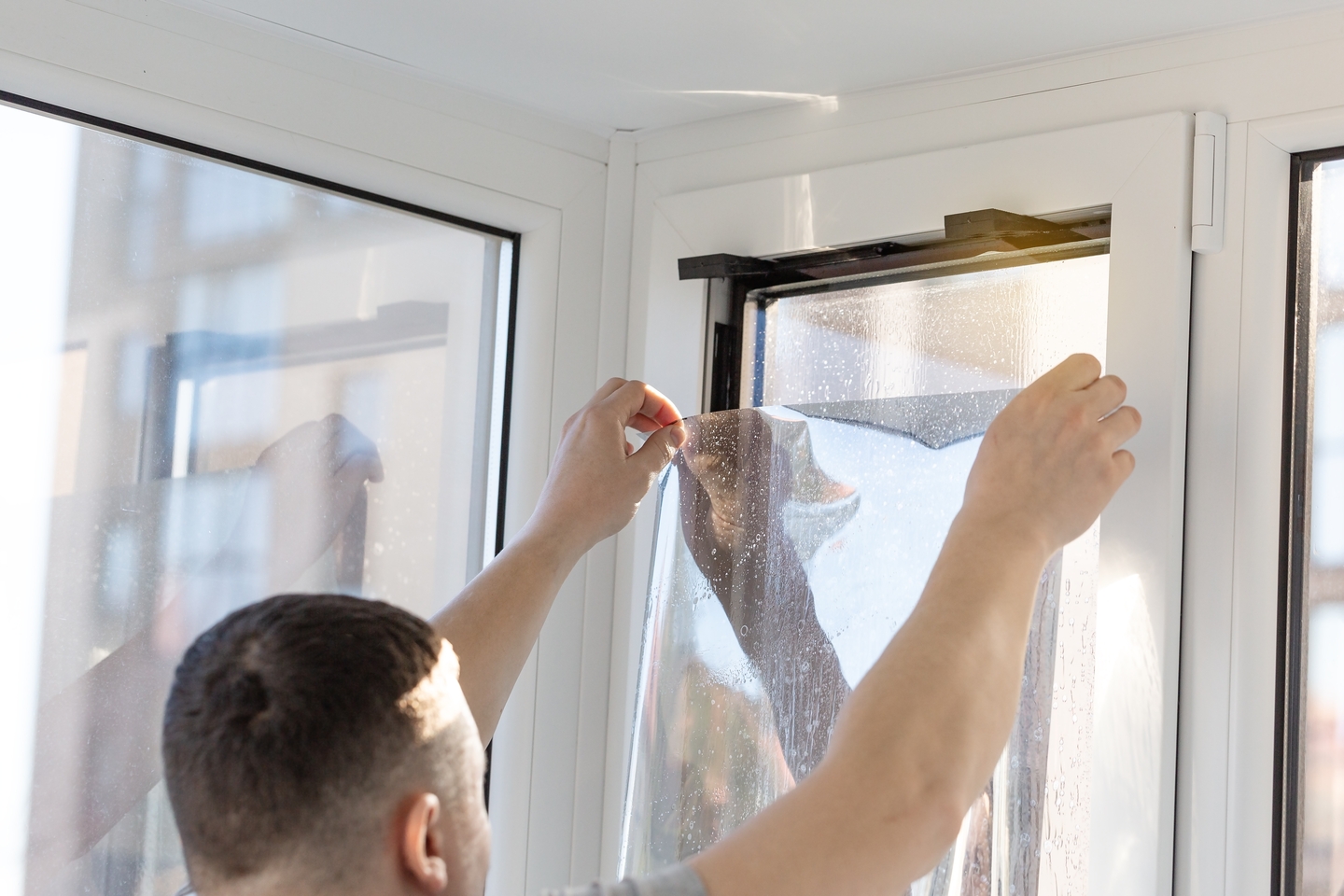 personne installant un film solaire sur une vitre
